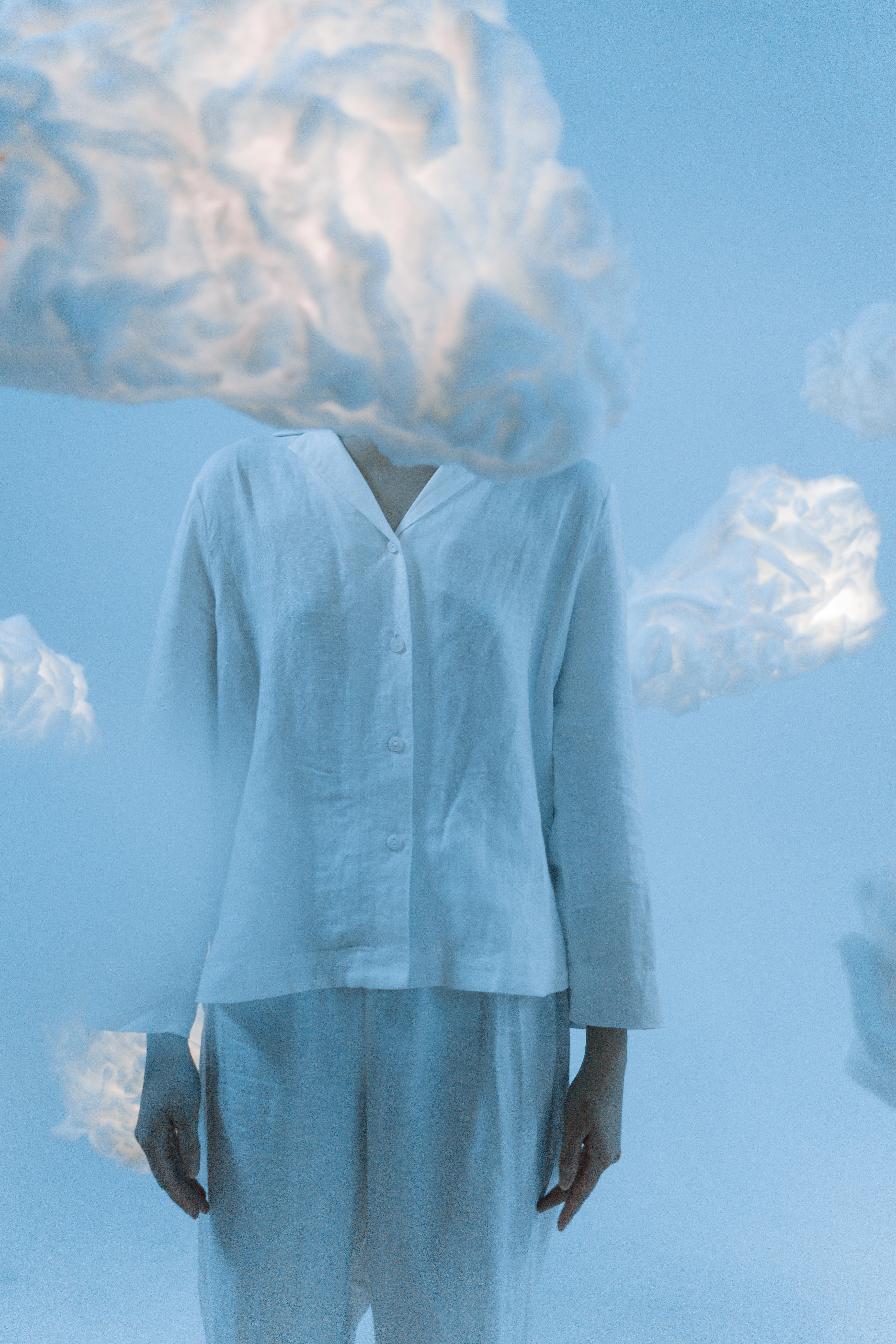 A surreal image featuring a person in a white outfit obscured by ethereal clouds.