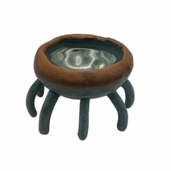 A ceramic bowl featuring six curved legs and a turquoise, glossy interior.