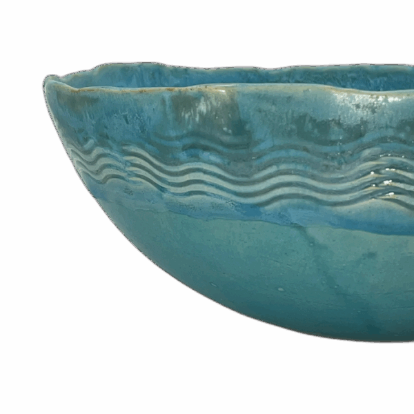 A glazed turquoise ceramic bowl with wavy surface patterns.
