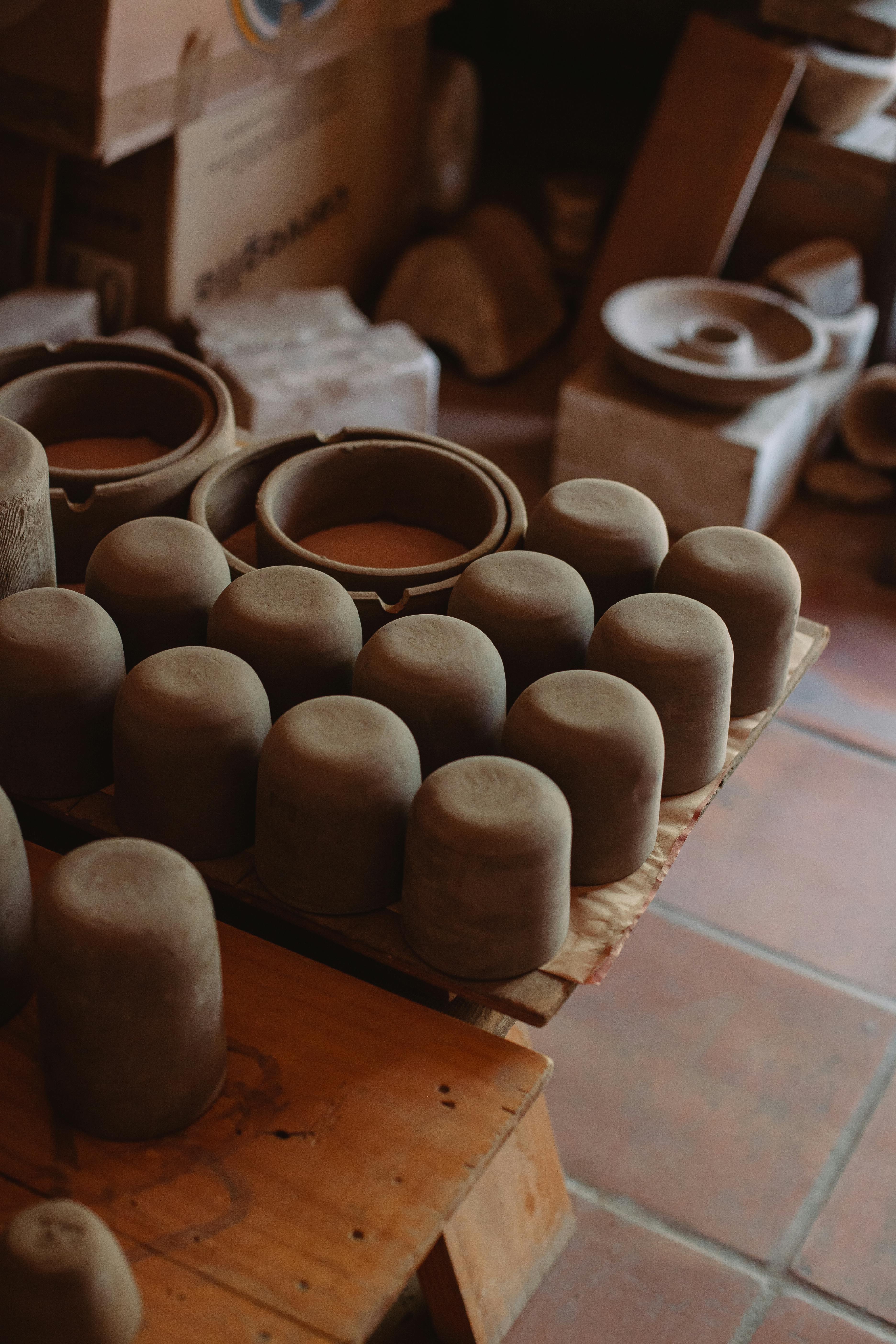 Collection of handcrafted clay pots in a warm and rustic artisan workshop setting.