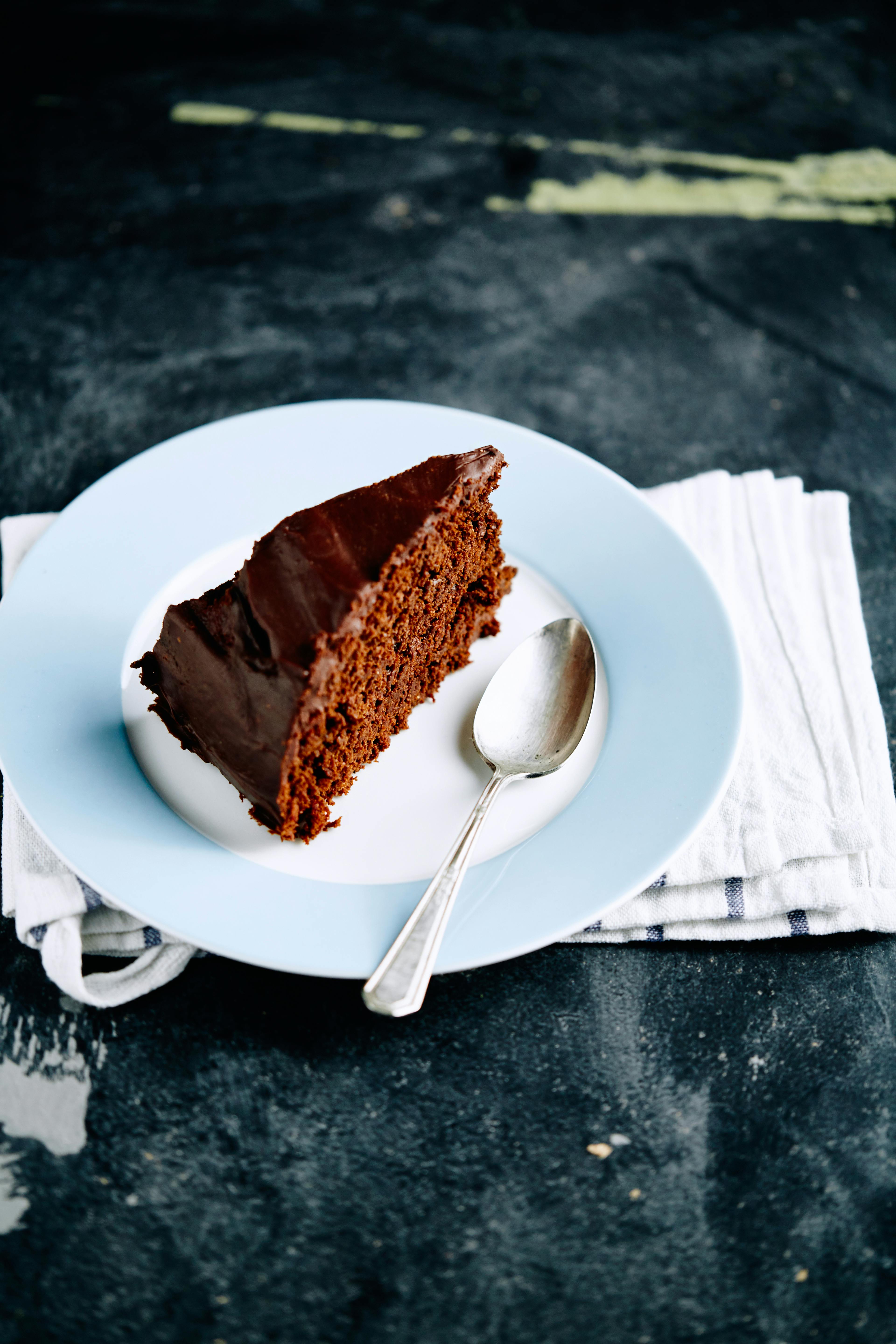 Indulge in a rich chocolate cake slice on a simple plate, perfect for dessert.