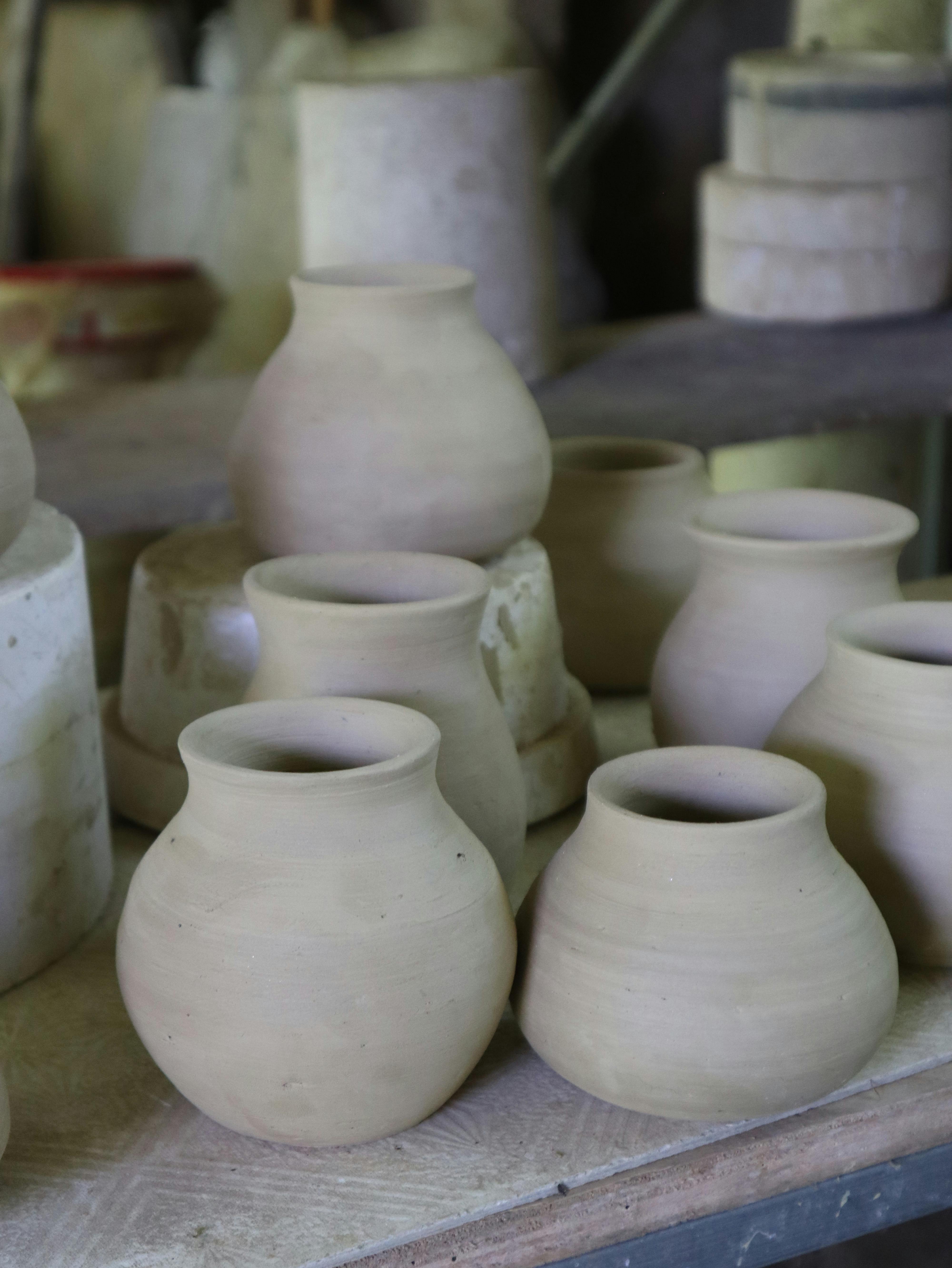 Handmade clay pots displayed on shelves in a rustic workshop setting, showcasing traditional pottery craftsmanship.