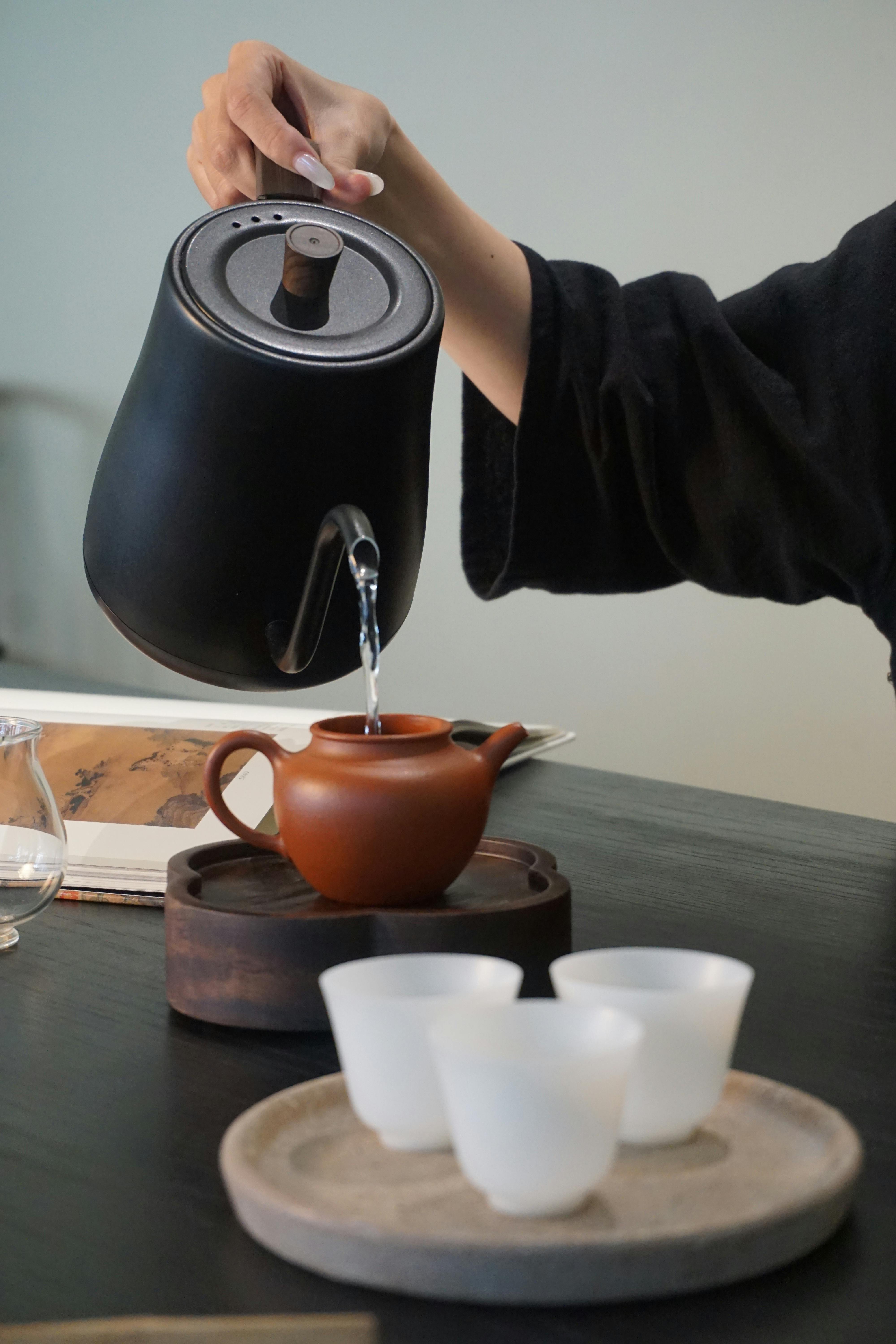 Elegant tea pouring in a serene setting with ceramic teapot and tea cups.