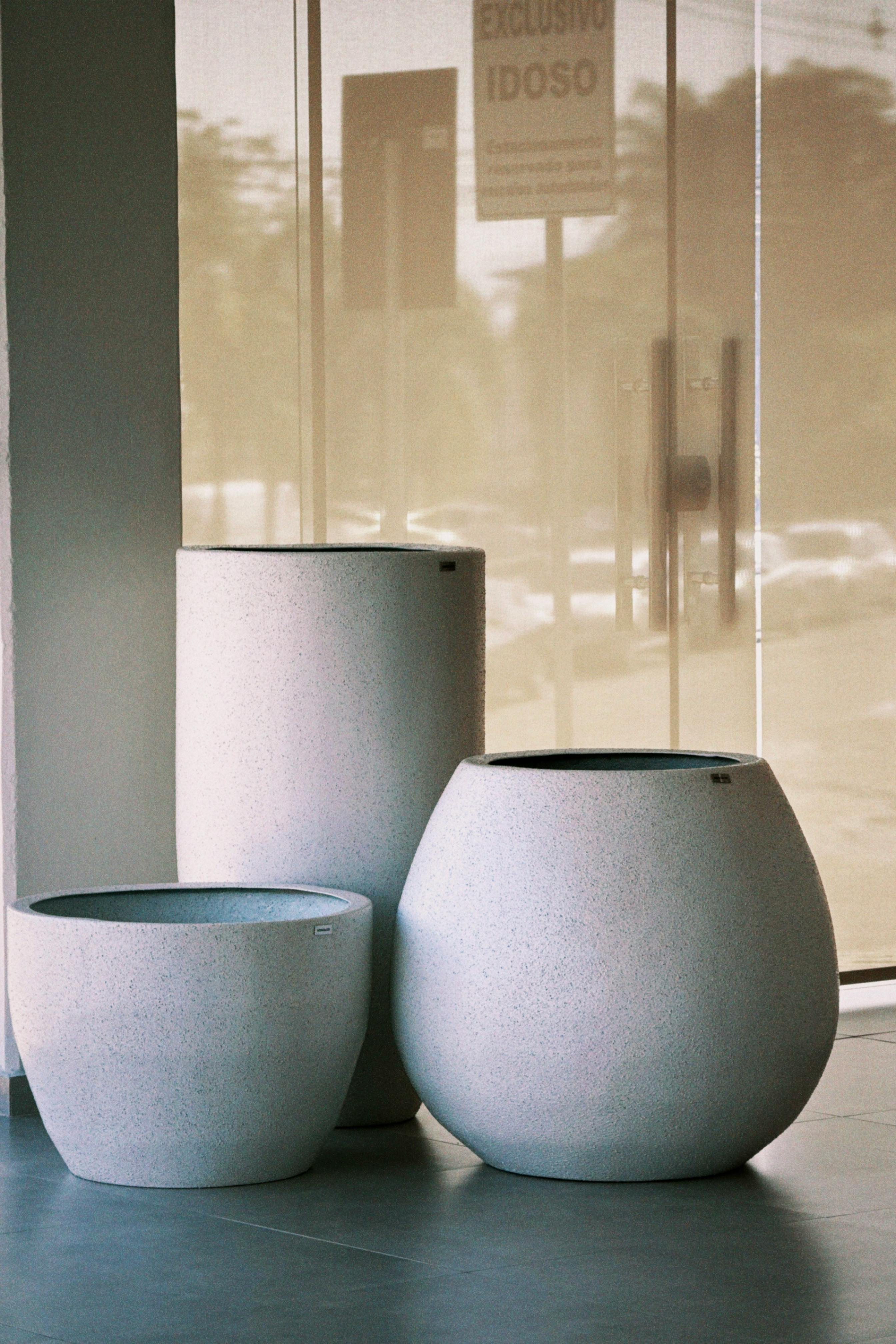 Minimalist trio of unique ceramic planters with bright natural light indoors.