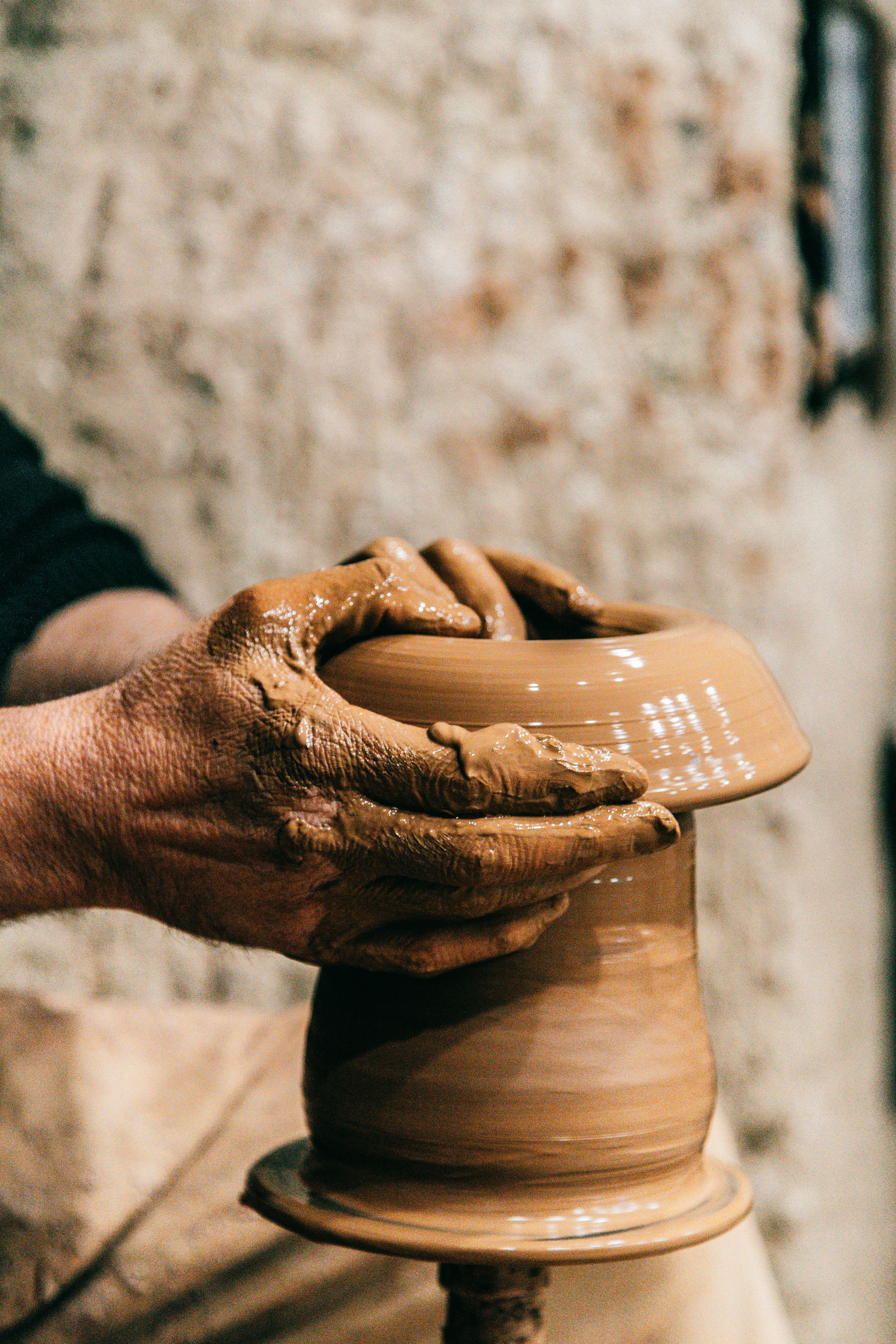 Crop anonymous craftsman doing pottery with clay and special equipment on blurred background