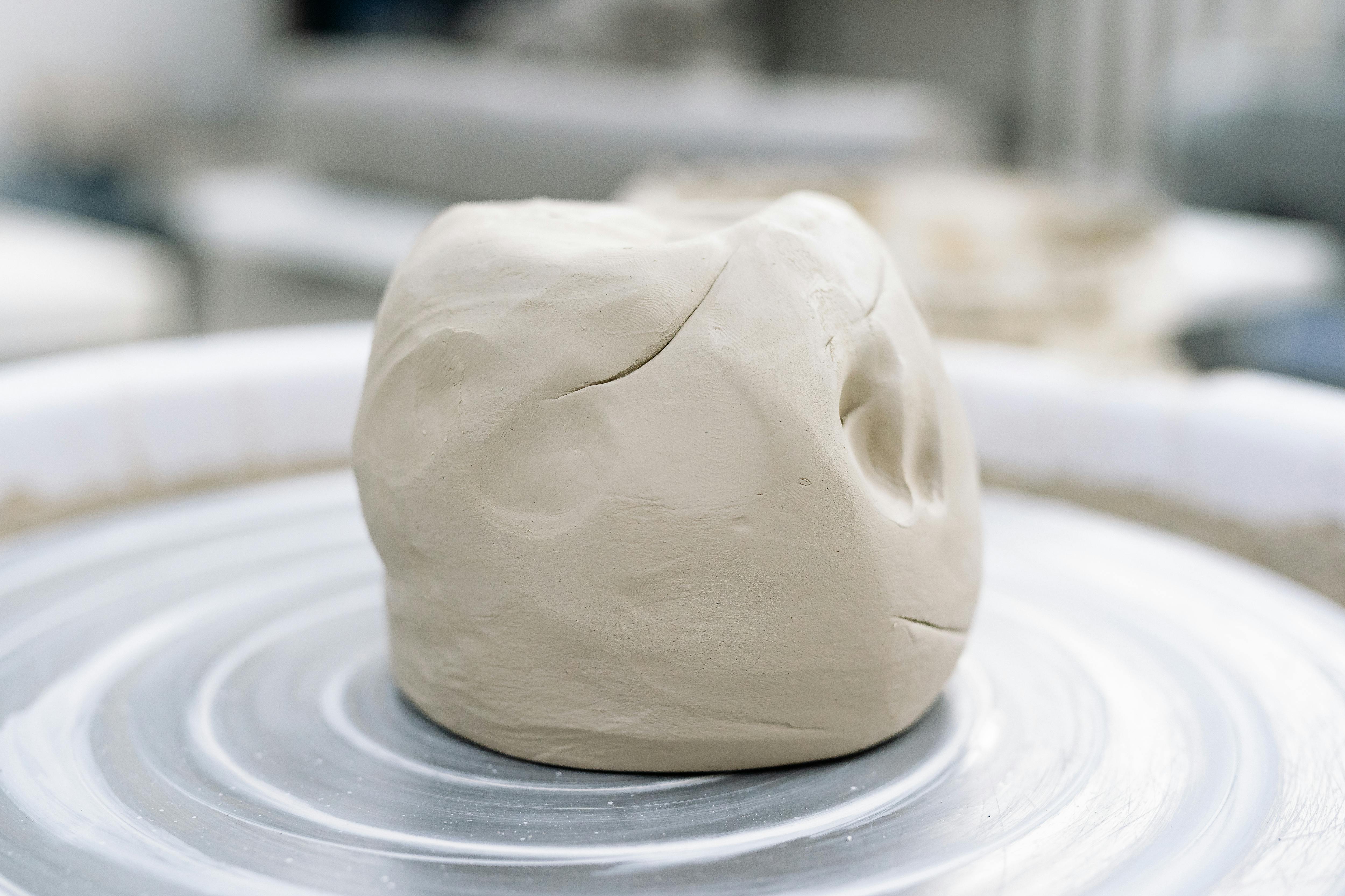 A lump of clay sits on a spinning pottery wheel in an art studio, ready for crafting.