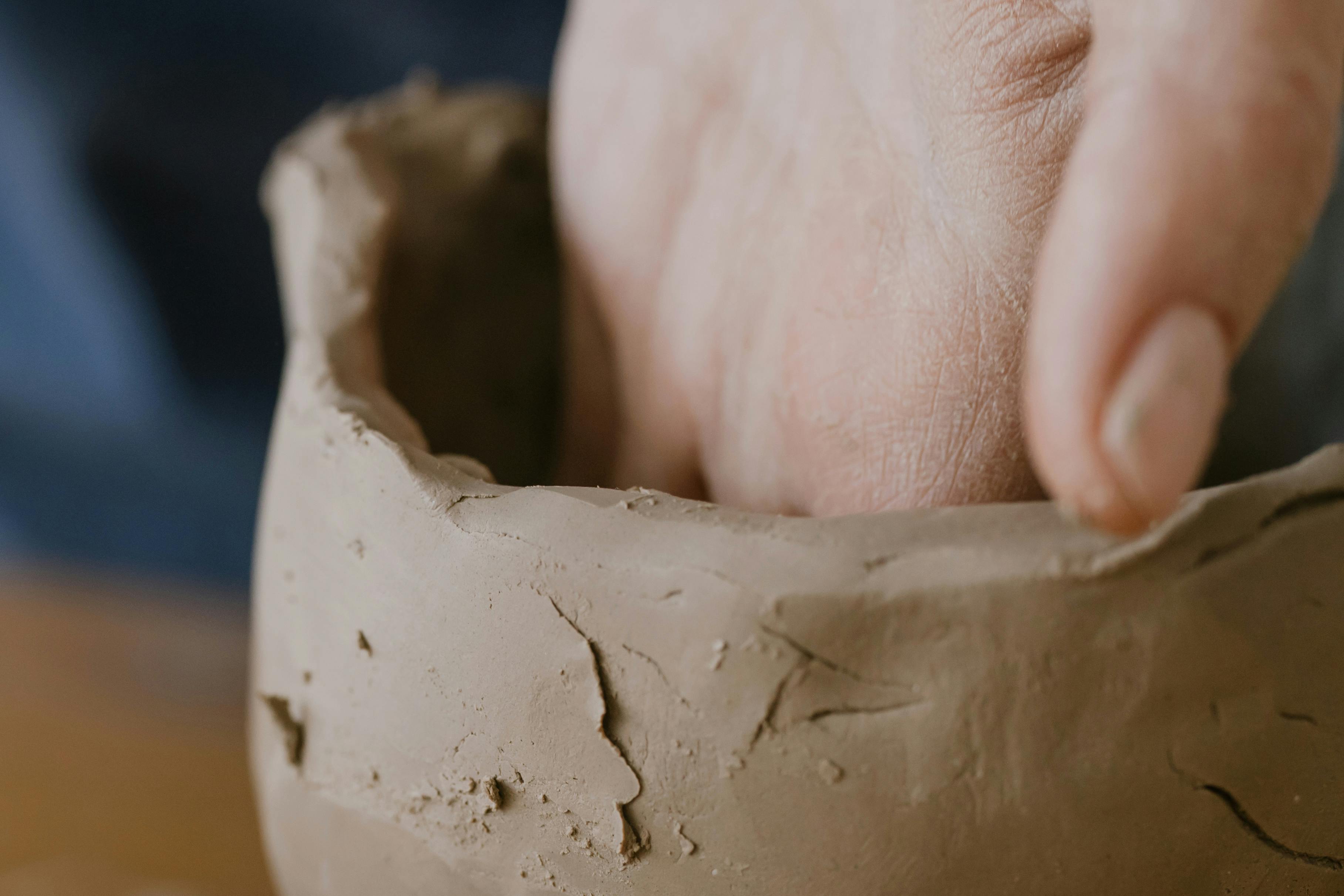 Artisan hand shaping a clay pot, highlighting craftsmanship and creativity in a pottery studio.