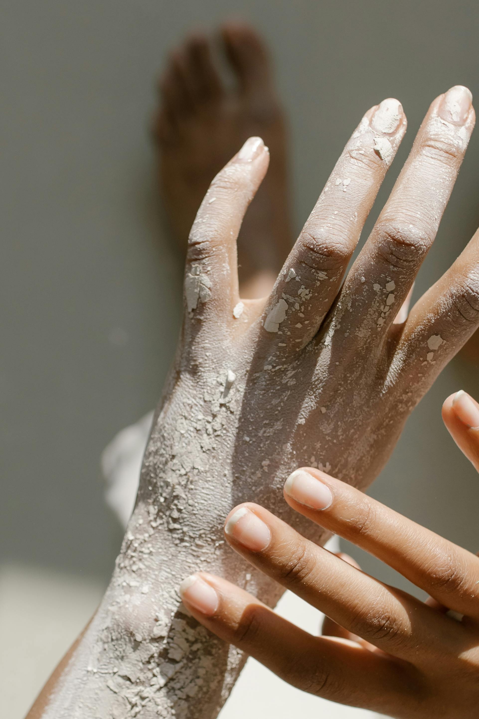 A detailed view of hands covered with clay, showcasing artistic texture and natural light.