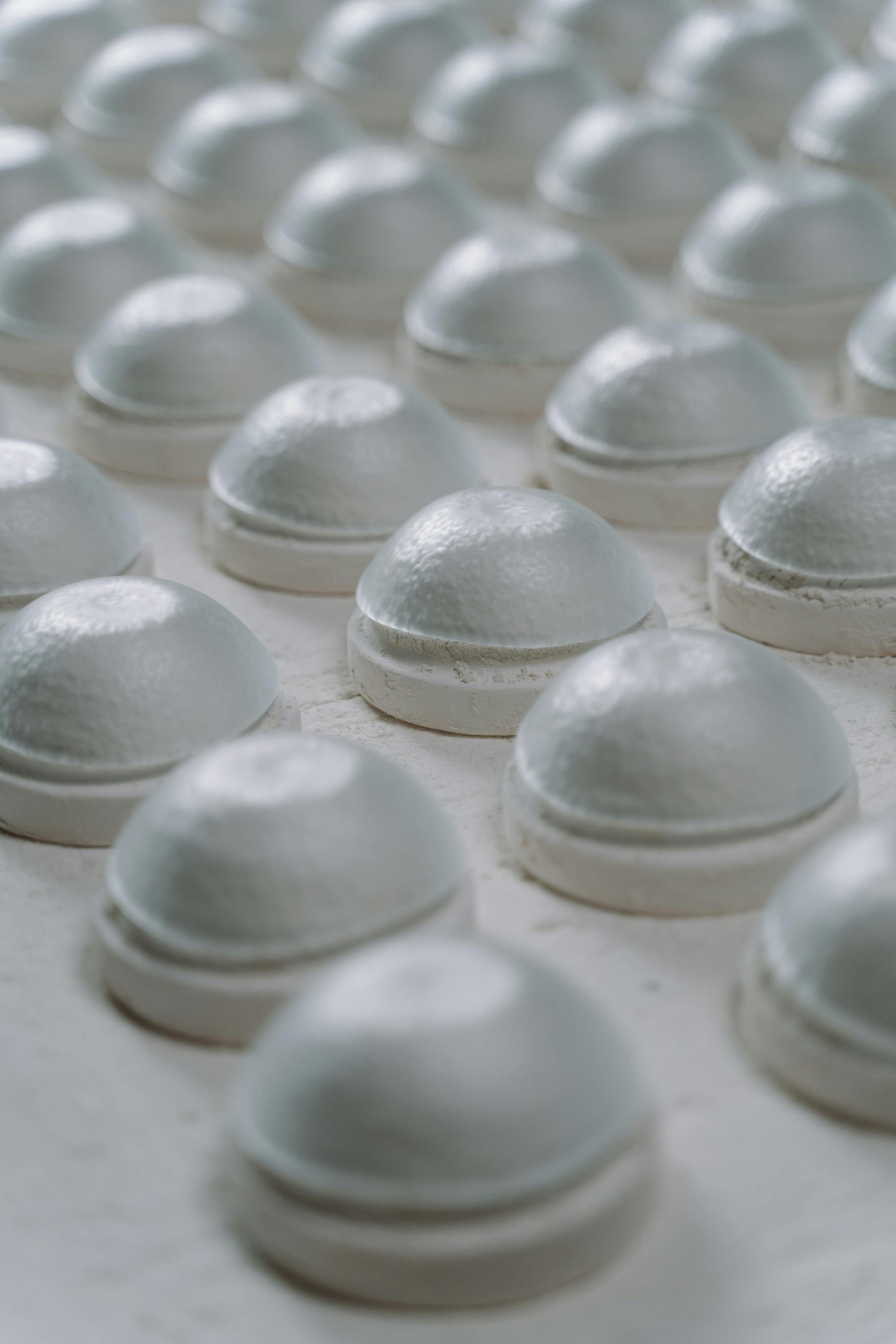 Detailed view of white ceramic bowl tops arranged in rows on a work surface.