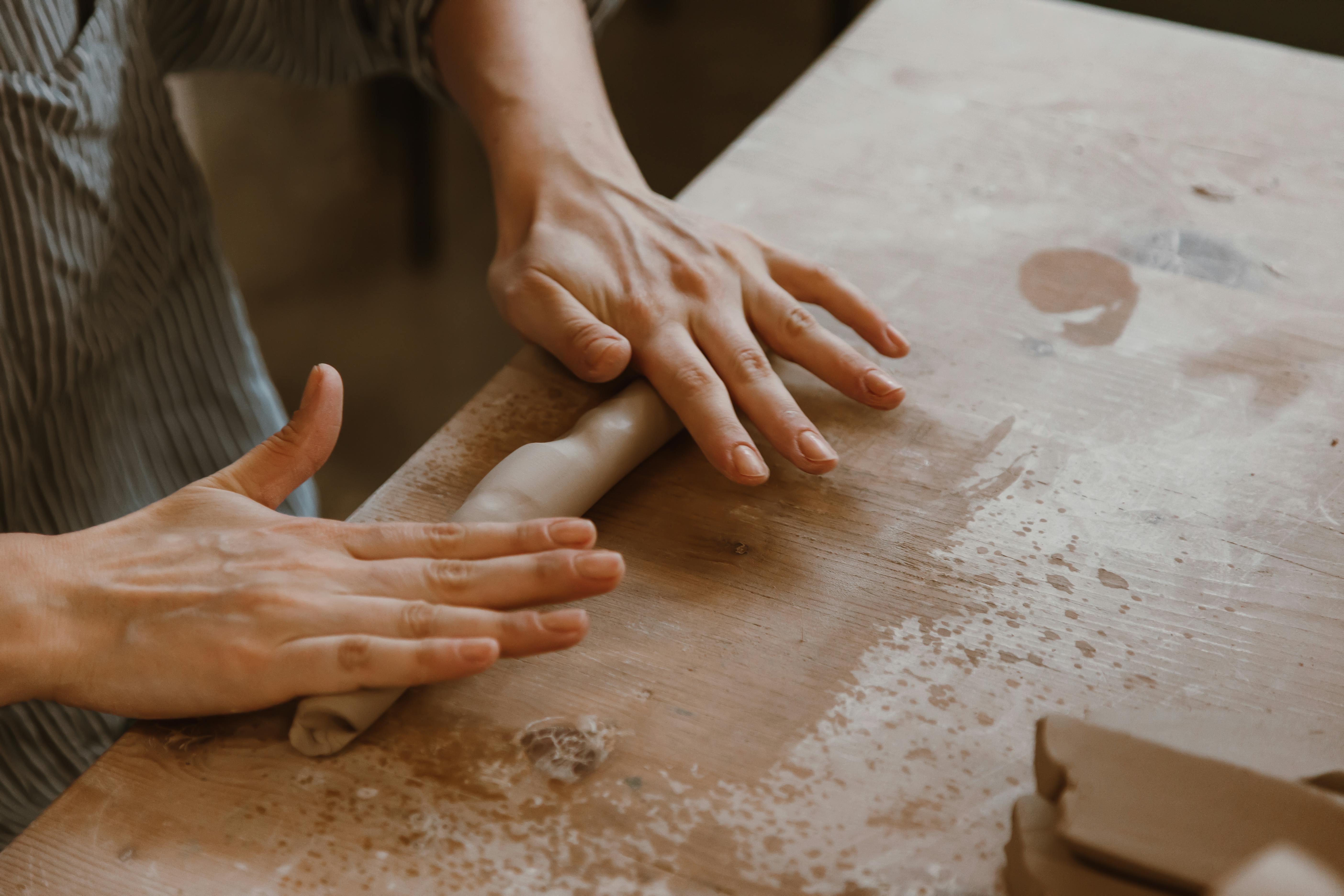 Detailed close-up of hands crafting clay on an artisan's table.