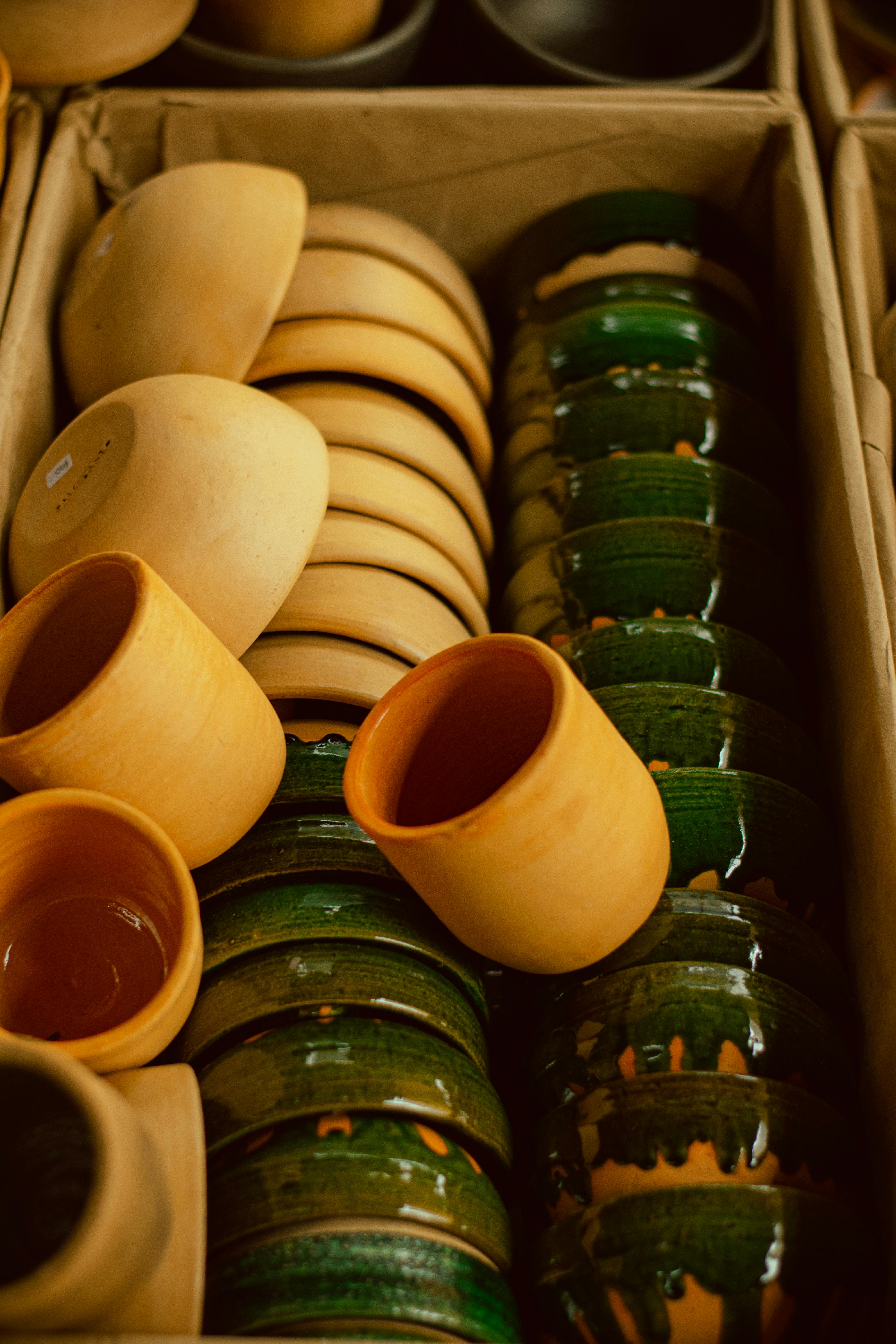 A vibrant collection of clay and ceramic pots arranged neatly in a cardboard box, showcasing traditional craftsmanship.